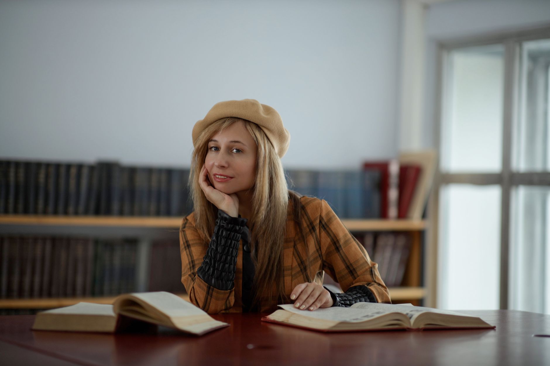 Elegancka kobieta w berecie czyta książki w bibliotece