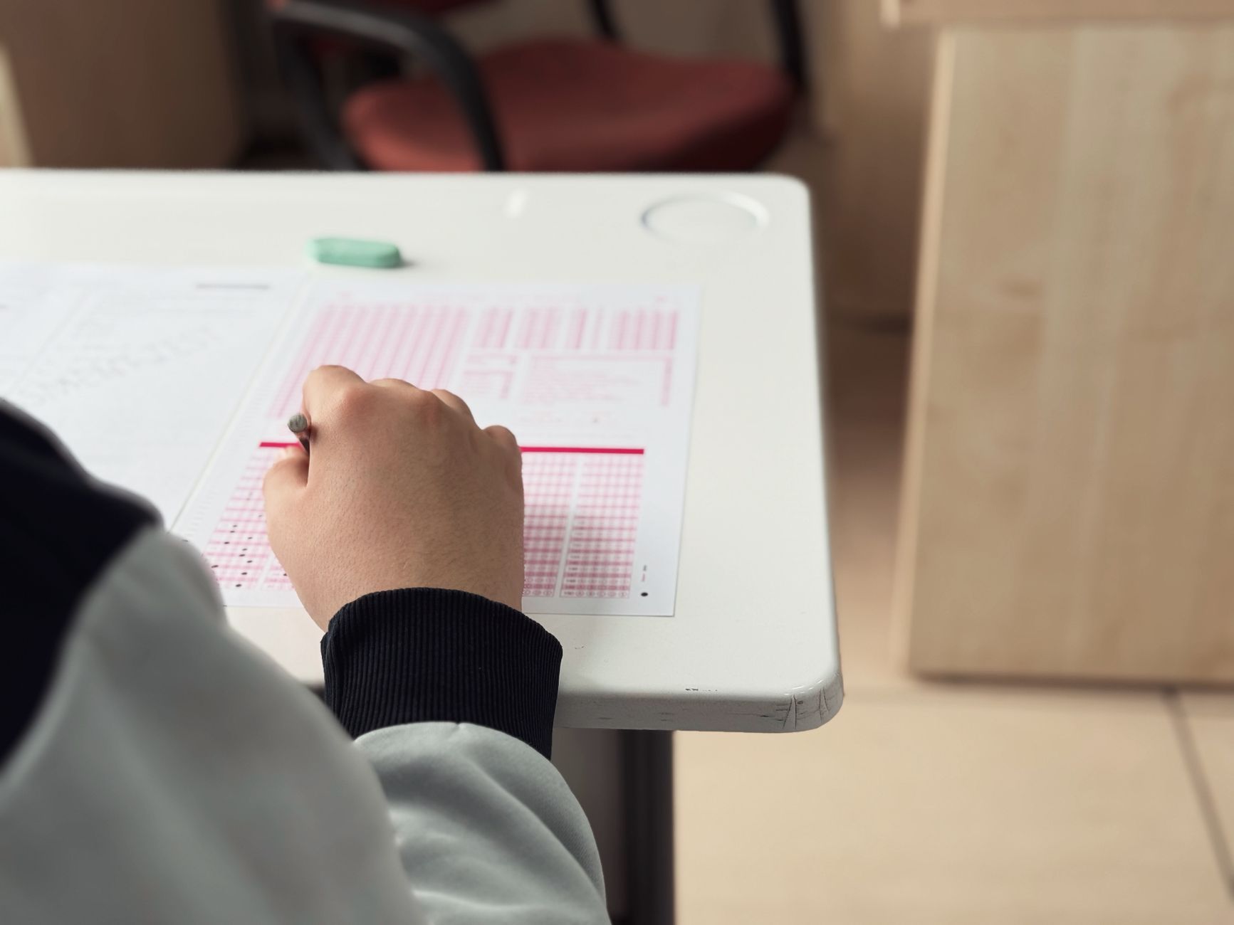 Uczeń pisze odpowiedź na test przy szkolnej ławce