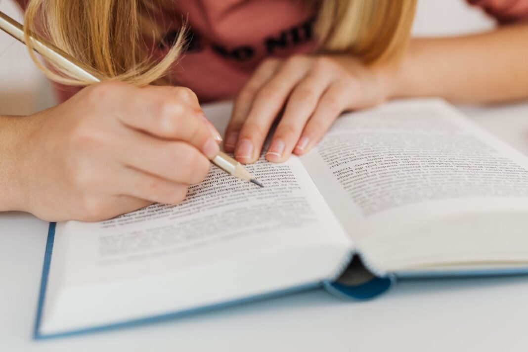 Dłonie kobiety zapisujące notatki w otwartej książce
