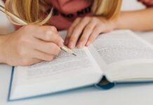 Academic vocabulary do IELTS Writing Task 2: zwroty, których używać z umiarem Dłonie kobiety zapisujące notatki w otwartej książce