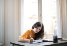 PEEL, TEEL czy PEE: który schemat akapitu wybrać w essay writing? Młoda kobieta pisząca w notesie przy słonecznym oknie