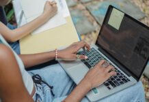 Studentki pracujące nad zadaniem z laptopem i notatkami w parku